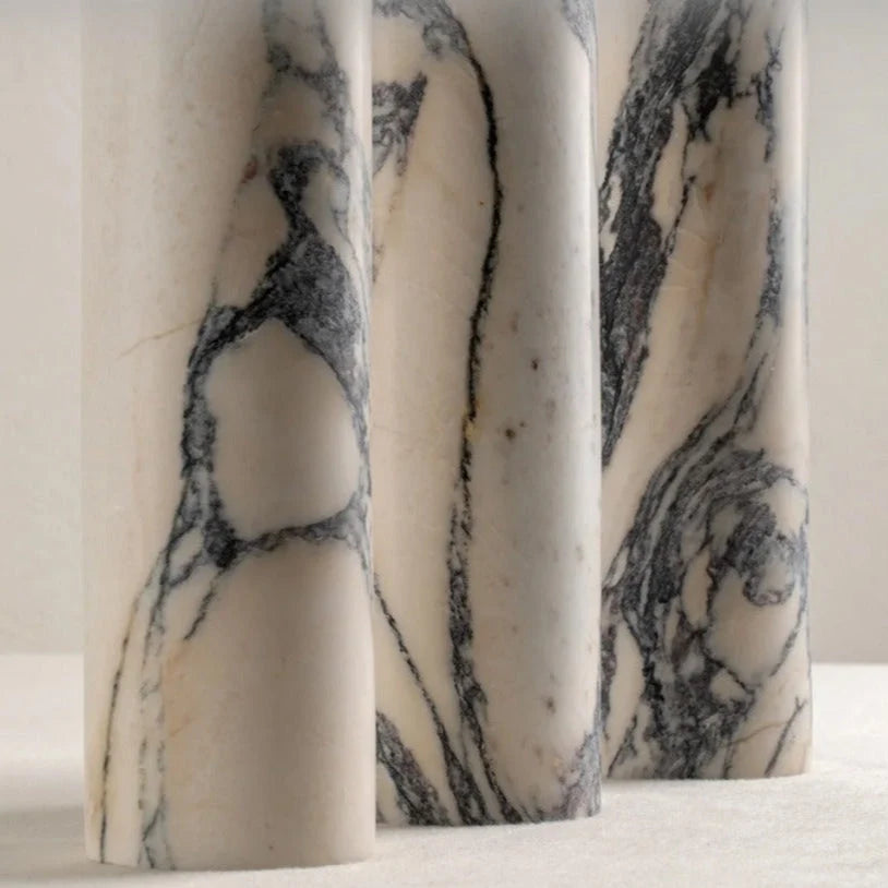 Close-up of three cylindrical white marble lamp bases featuring distinctive grey and black veining, showcasing the natural stone texture for modern decor.