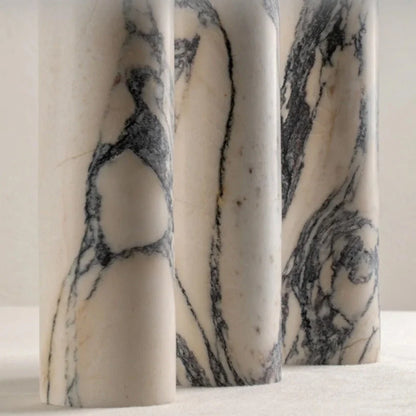 Close-up of three cylindrical white marble lamp bases featuring distinctive grey and black veining, showcasing the natural stone texture for modern decor.