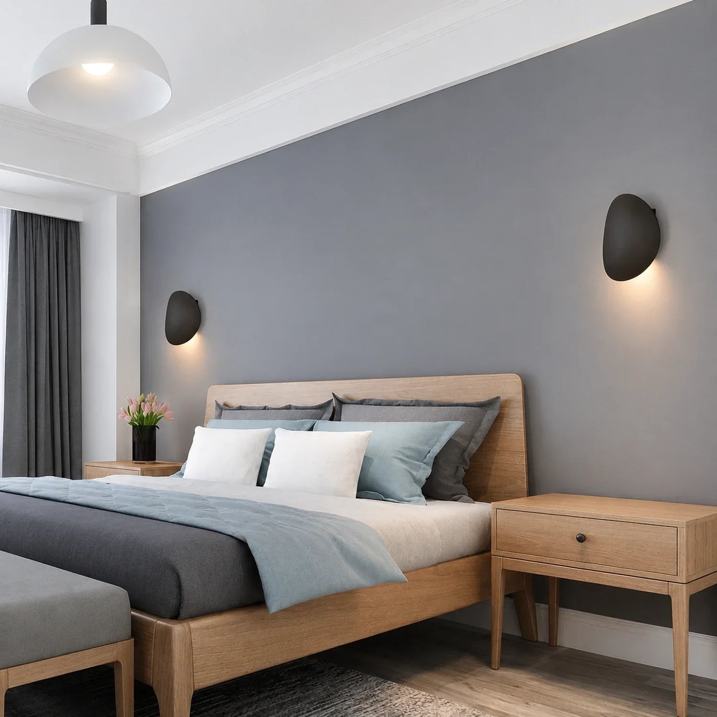 Modern black aluminium LED wall lights mounted on a grey bedroom wall, providing soft up and down illumination above a wooden bed and bedside tables.