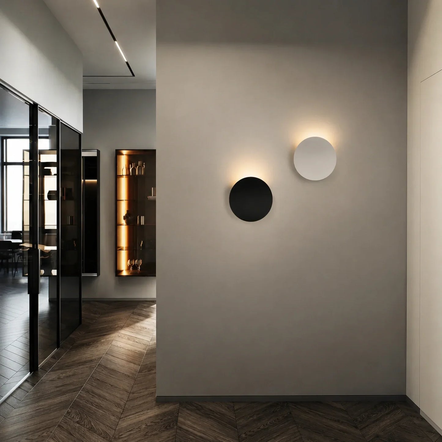 Two circular modern aluminium LED wall lights mounted on a grey interior wall, featuring soft up and down illumination in a contemporary hallway.