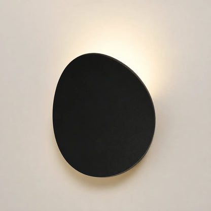 Modern black circular LED wall light mounted on a neutral wall, casting a soft, warm glow from the top and bottom edges for a stylish ambient effect.