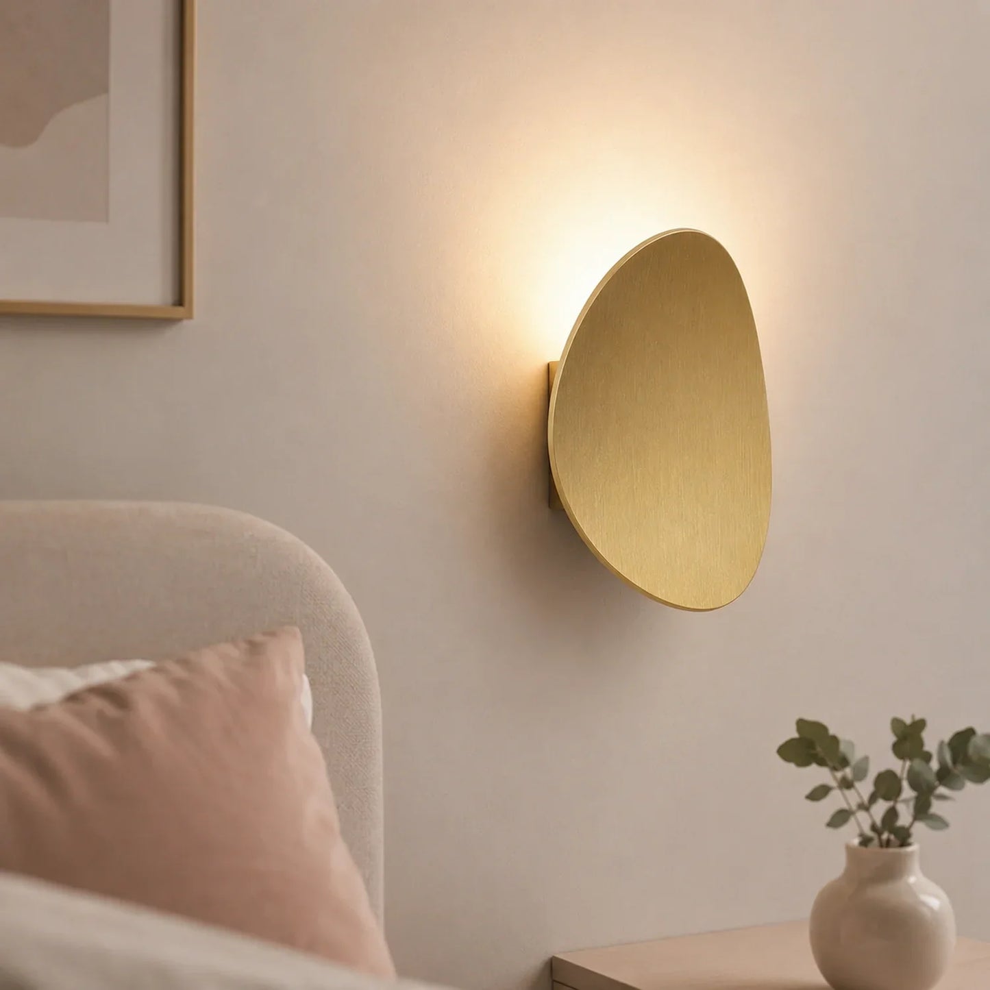 Modern gold aluminium LED wall light with warm illumination mounted above a bedside table in a contemporary bedroom setting.