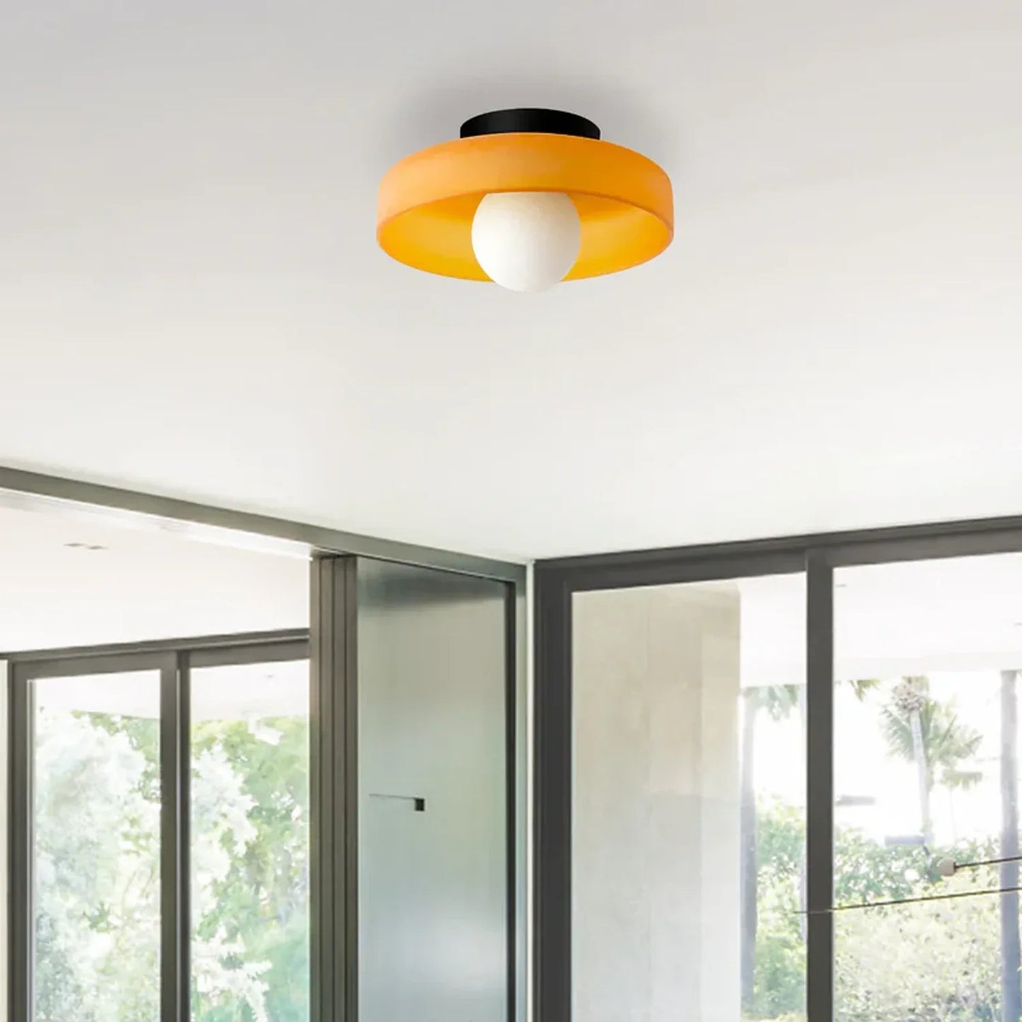 Modern Bauhaus flush mount ceiling light featuring a vibrant orange circular shade and a central white glass bulb, installed in a contemporary room.