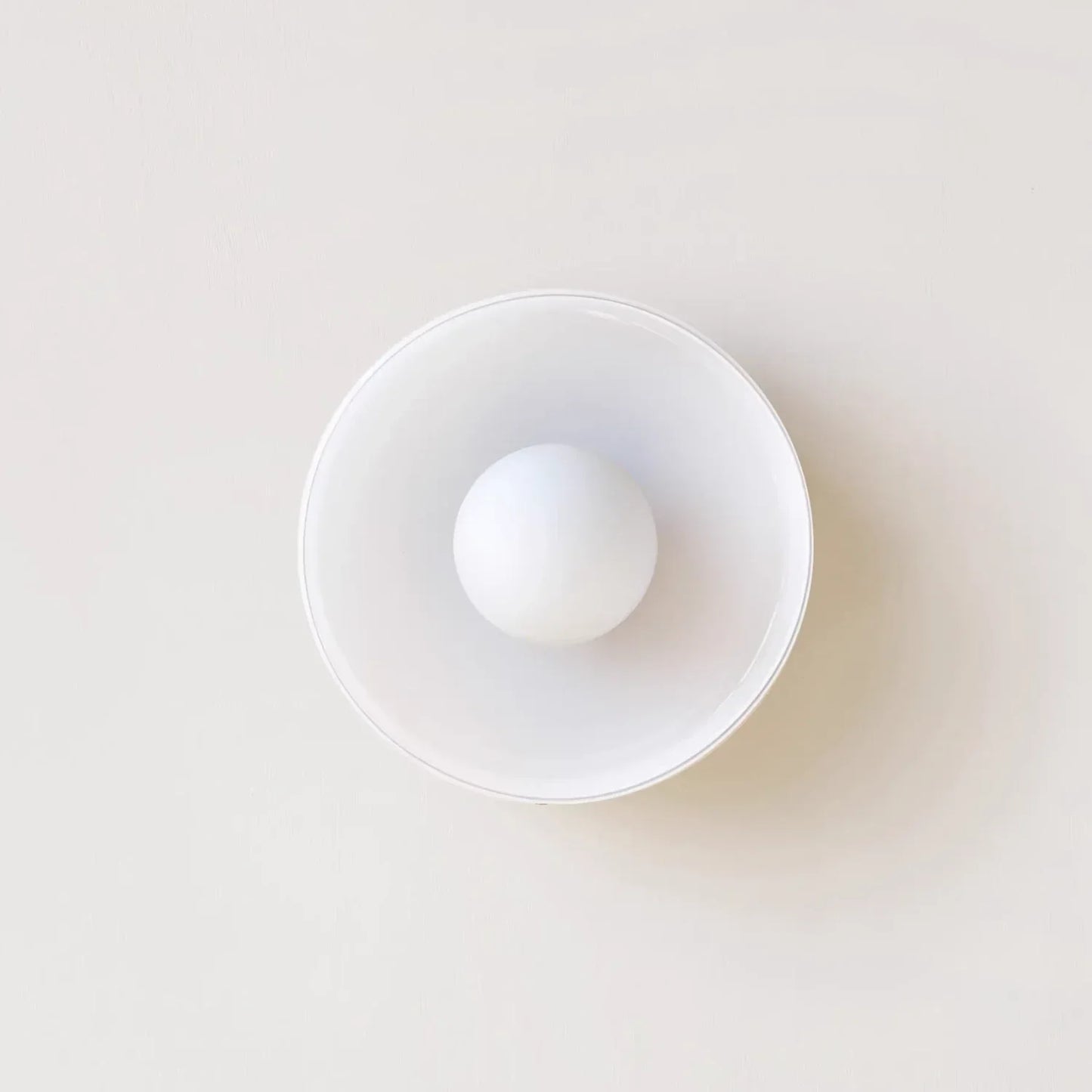 Modern Bauhaus flush mount ceiling light featuring a minimalist circular glass shade with a central spherical bulb, viewed from directly below.