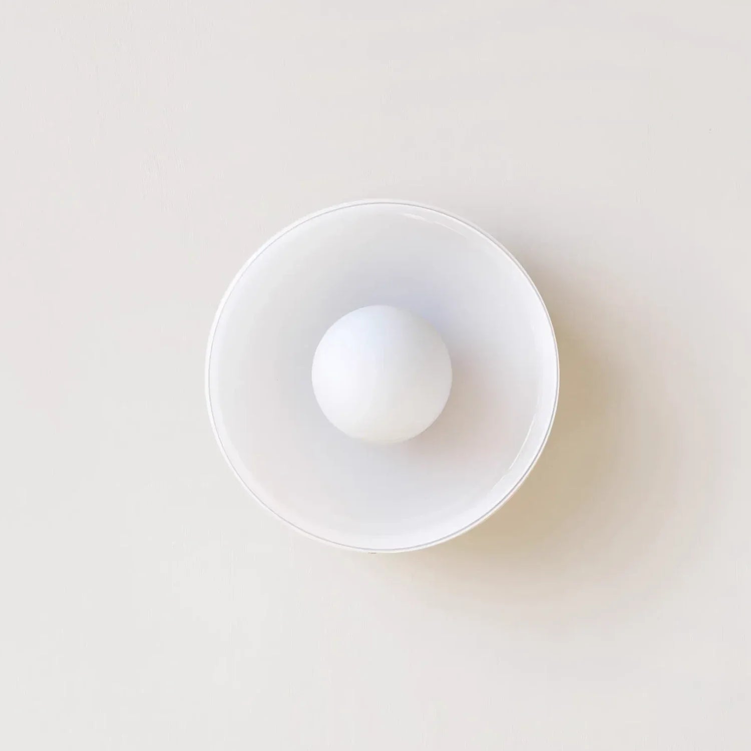 Modern Bauhaus flush mount ceiling light featuring a minimalist circular glass shade with a central spherical bulb, viewed from directly below.