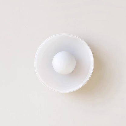 Modern Bauhaus flush mount ceiling light featuring a minimalist circular glass shade with a central spherical bulb, viewed from directly below.