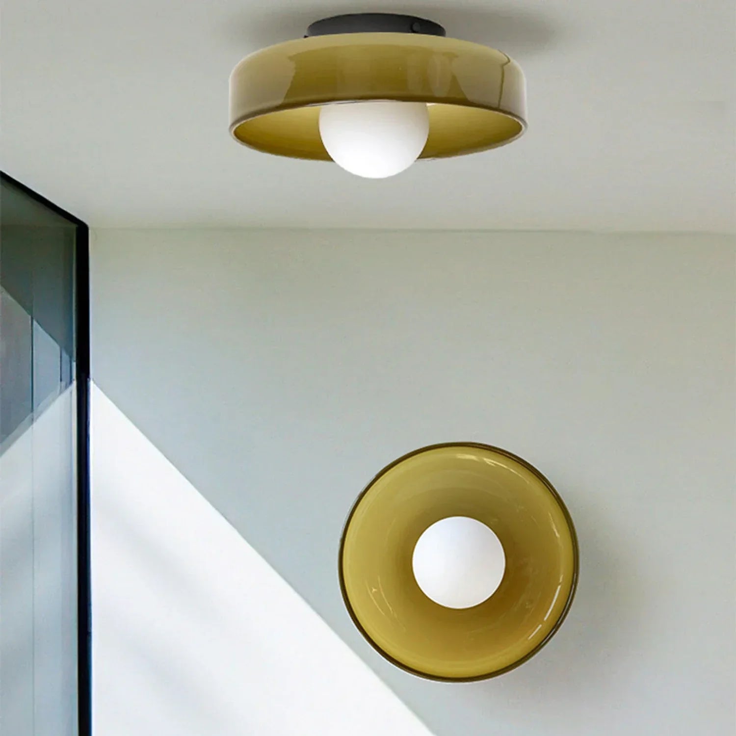 Modern Bauhaus flush mount ceiling light featuring a circular olive green glass shade and a central white globe bulb, mounted on a white ceiling.
