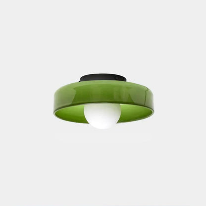 Modern Bauhaus style flush mount ceiling light featuring a glossy green glass shade with a central white bulb and a black iron base against a white backgro