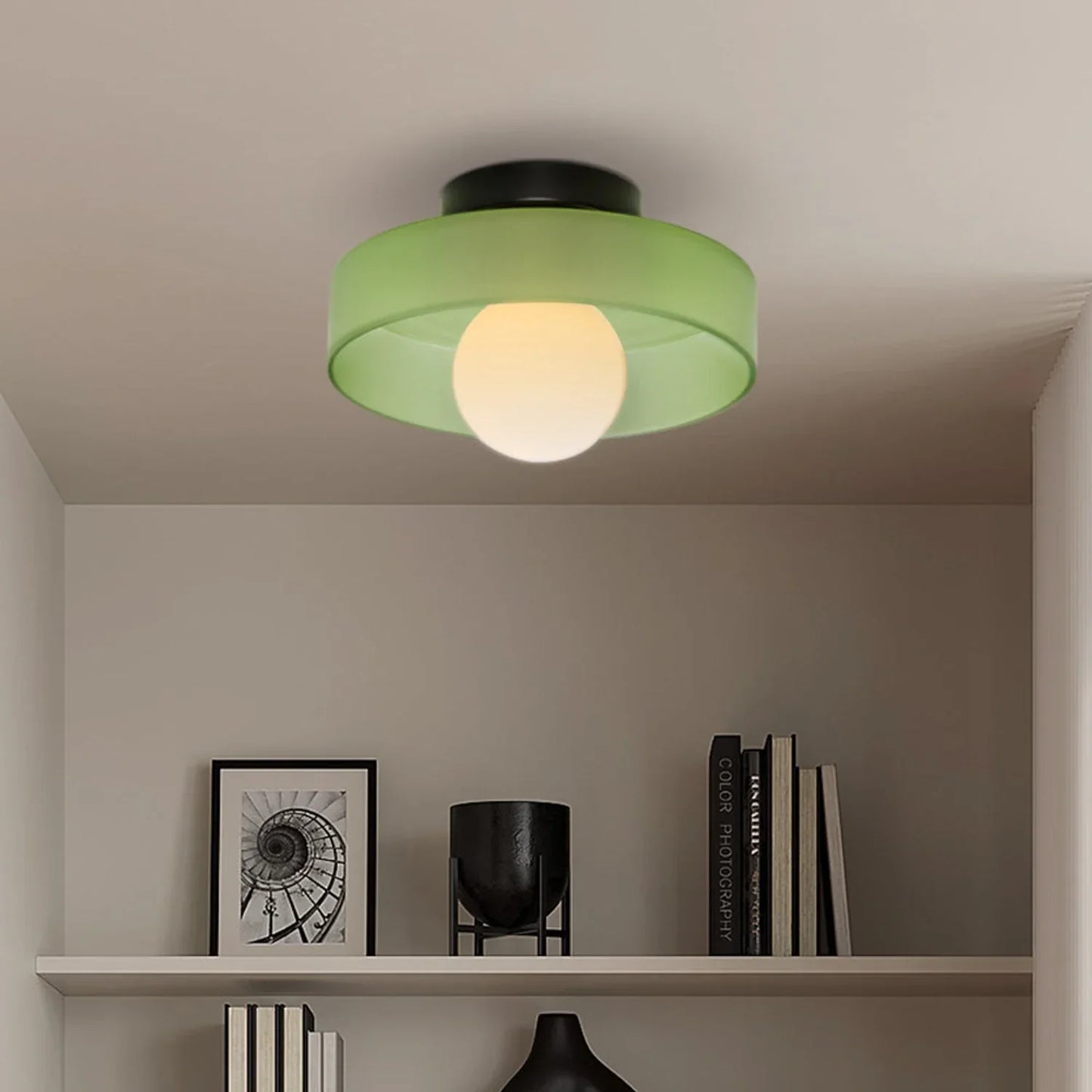 Modern Bauhaus style flush mount ceiling light featuring a green glass shade and a glowing central bulb, mounted on a neutral interior ceiling.