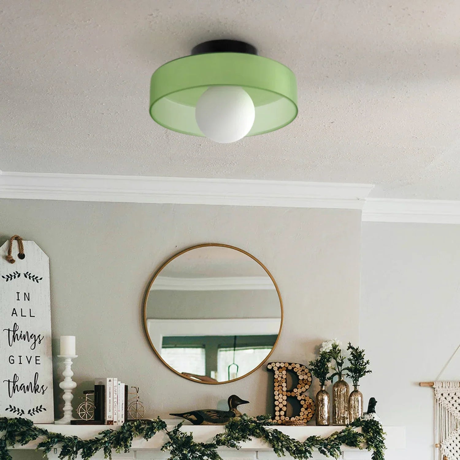 Modern Bauhaus flush mount ceiling light with a sage green drum shade and a central white globe bulb, installed in a stylish living room interior.