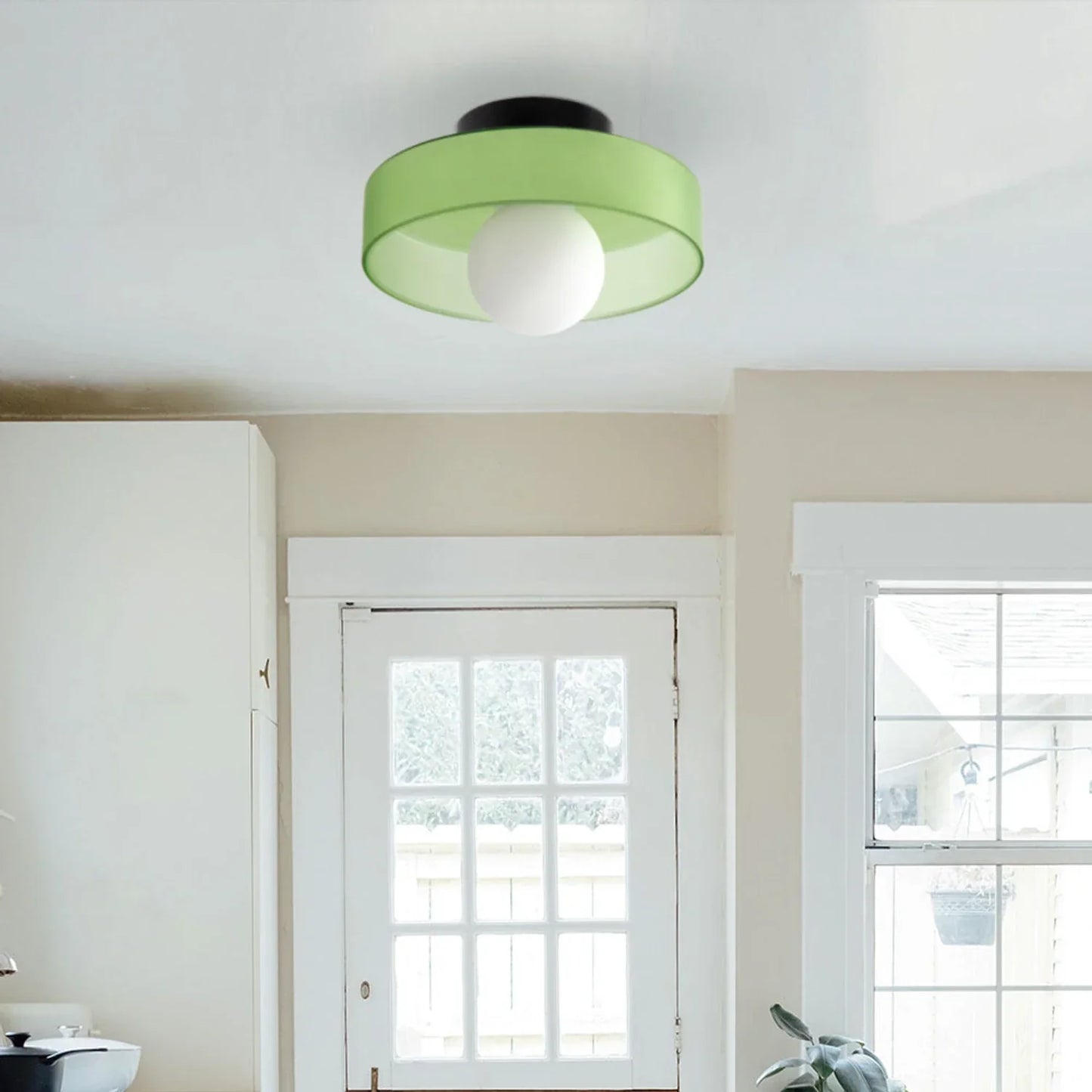 Modern Bauhaus flush mount ceiling light featuring a vibrant green circular shade and a central white glass globe bulb installed in a bright home interior.