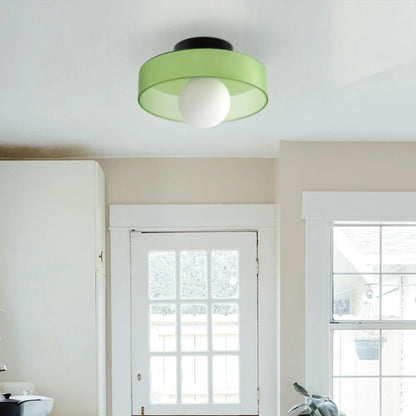 Modern Bauhaus flush mount ceiling light featuring a vibrant green circular shade and a central white glass globe bulb installed in a bright home interior.