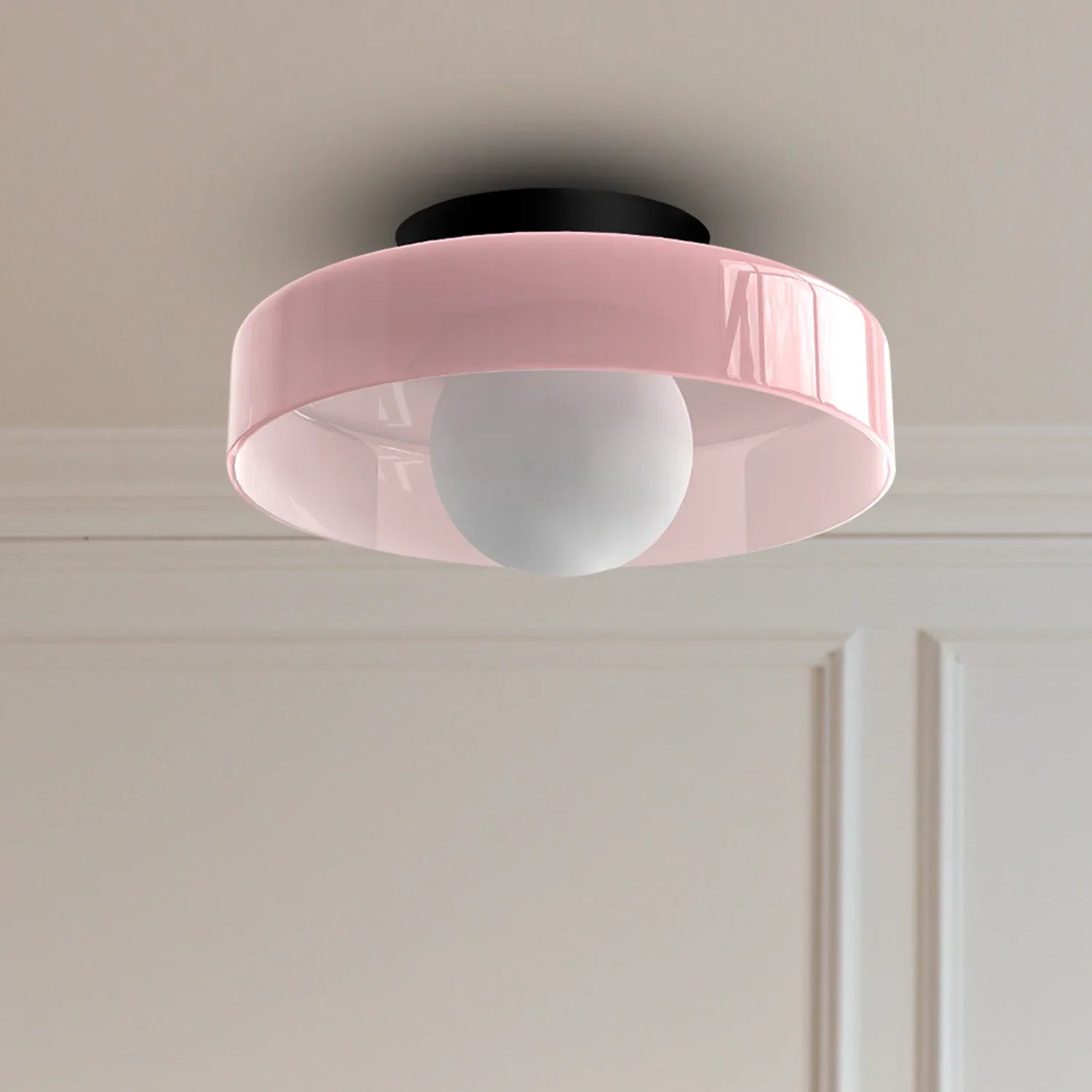 Modern Bauhaus flush mount ceiling light featuring a glossy pink circular shade and a central white globe bulb, mounted against a neutral wall.