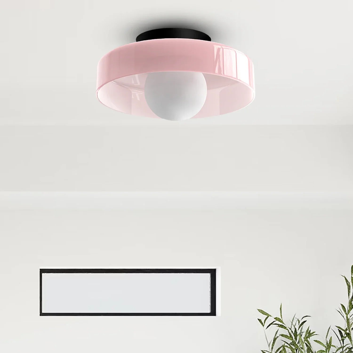 Modern Bauhaus flush mount ceiling light featuring a soft pink circular shade with a central white globe bulb, mounted on a black base in a room.
