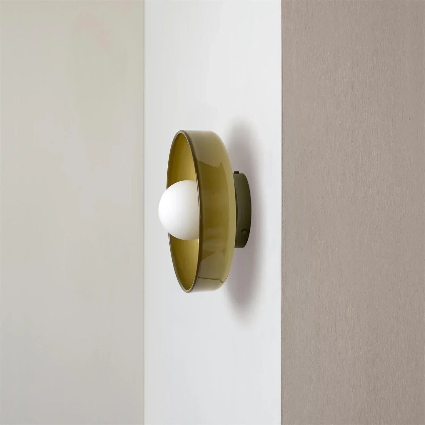 Modern Bauhaus style flush mount ceiling light featuring a circular olive green metal frame with a central white glass globe bulb mounted on a wall.