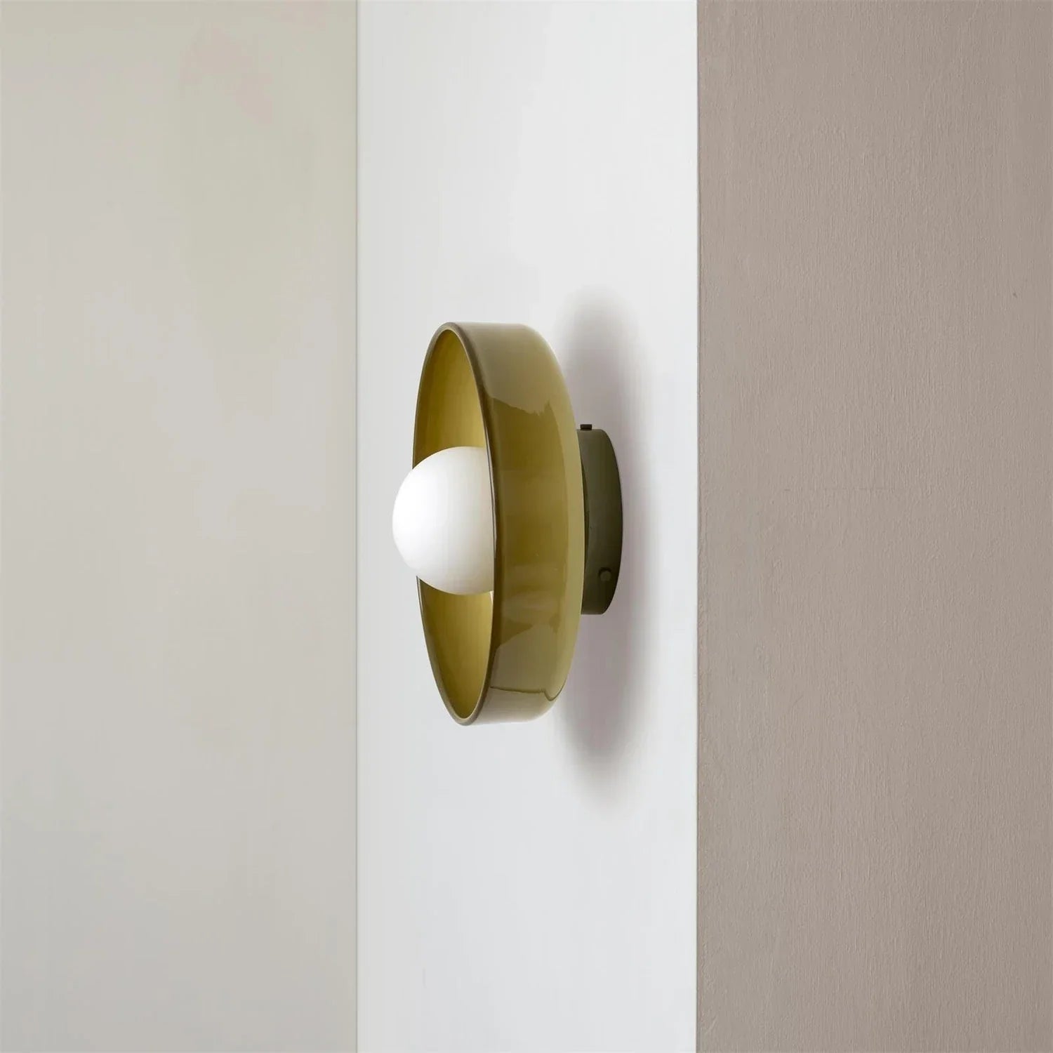 Modern Bauhaus style flush mount ceiling light featuring a circular olive green metal frame with a central white glass globe bulb mounted on a wall.