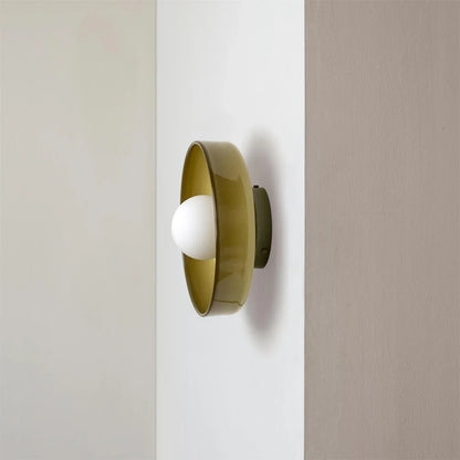 Modern Bauhaus style flush mount ceiling light featuring a circular olive green metal frame with a central white glass globe bulb mounted on a wall.