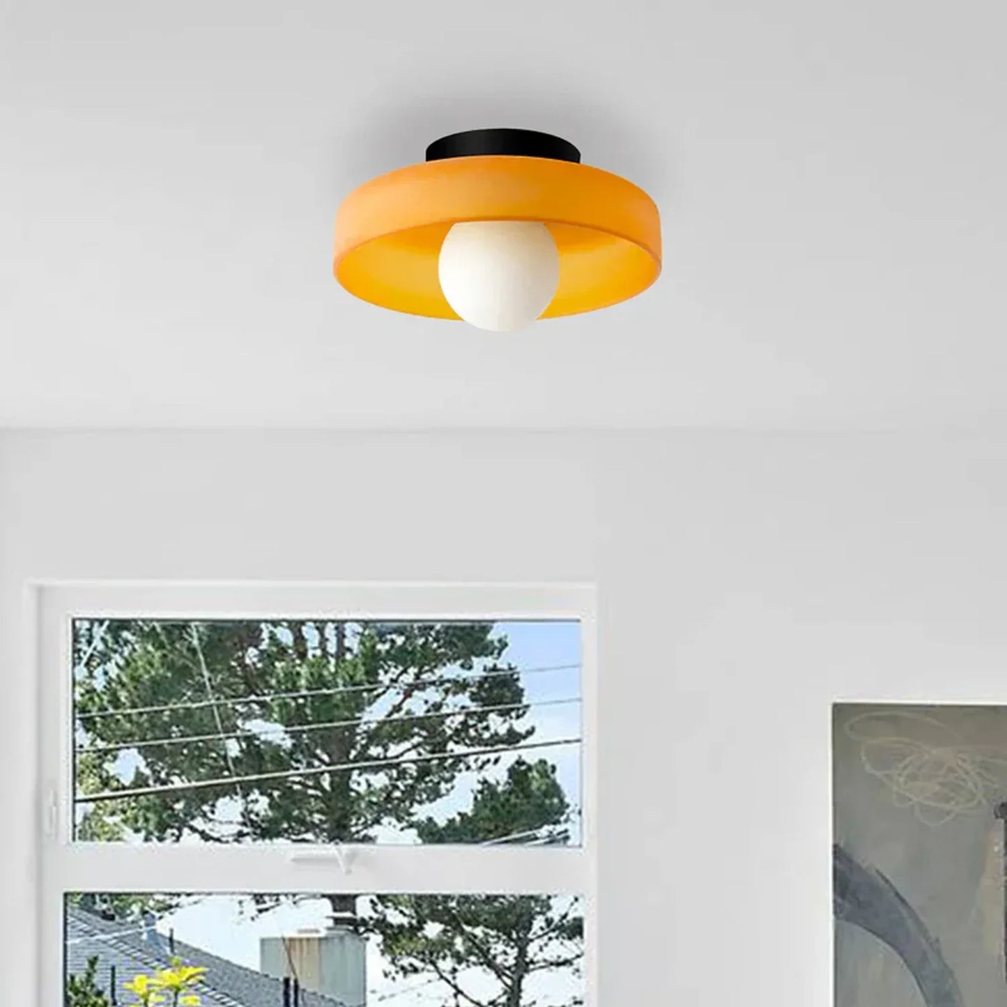 Modern Bauhaus flush mount ceiling light featuring a vibrant orange glass shade and a central white globe bulb, mounted on a black iron base.