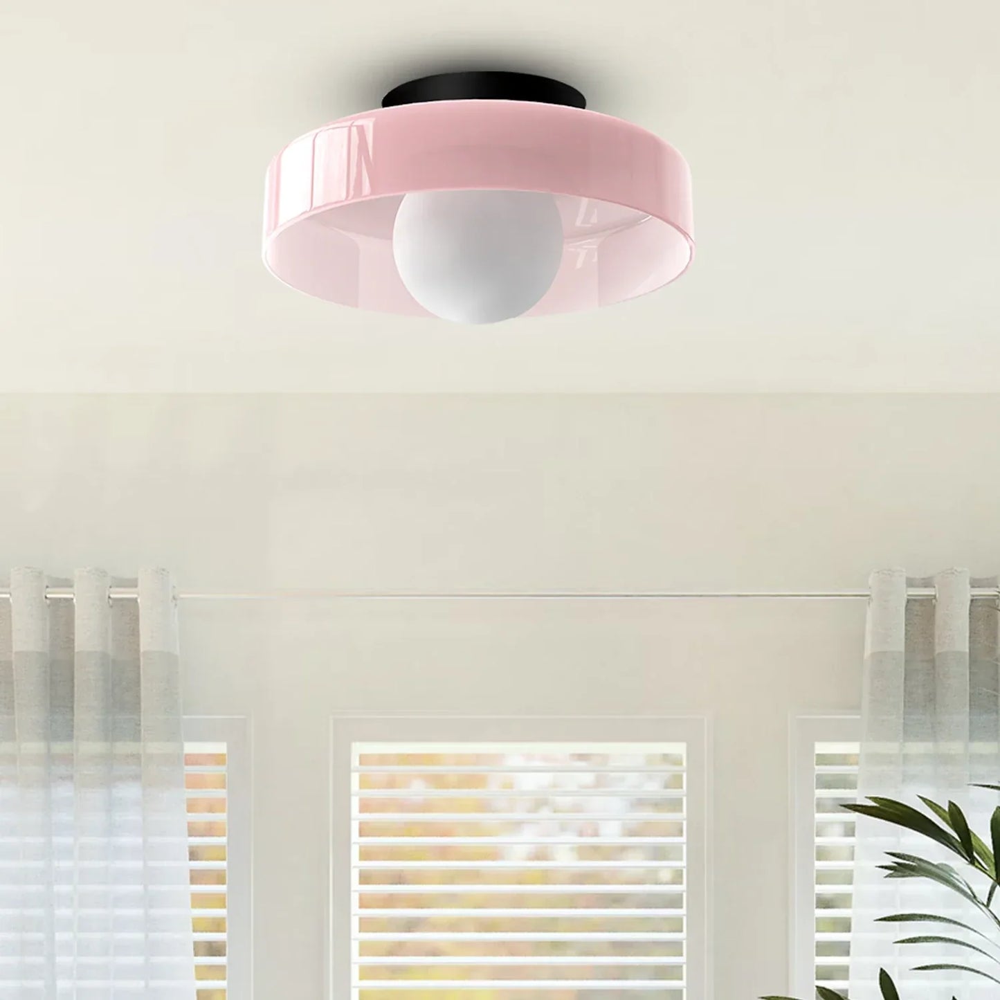 Modern Bauhaus style flush mount ceiling light featuring a pink circular shade and a central white glass globe bulb, mounted on a white ceiling.
