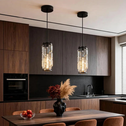 Two modern crystal pendant lights with black cords hanging over a wooden dining table, providing warm illumination in a stylish kitchen sett