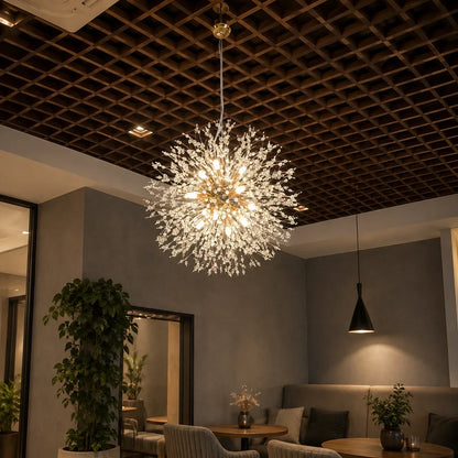 Modern dandelion LED pendant light featuring a spherical crystal design, suspended in a contemporary interior with a dark coffered ceiling and seating.