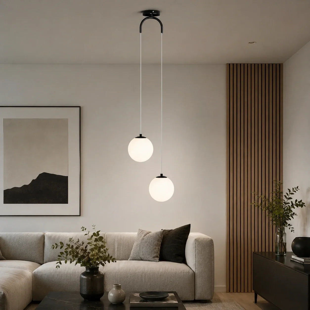 Modern ceiling pendant light featuring two glowing white glass globes suspended at different heights above a contemporary living room sofa.