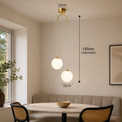 Modern gold two-head glass globe pendant light with adjustable 150cm drop, featuring two 15cm spherical shades hanging above a dining table interior.