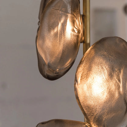Close-up of the textured amber glass shades on a modern brass LED floor lamp, showing the warm glow of the illuminated organic shapes.