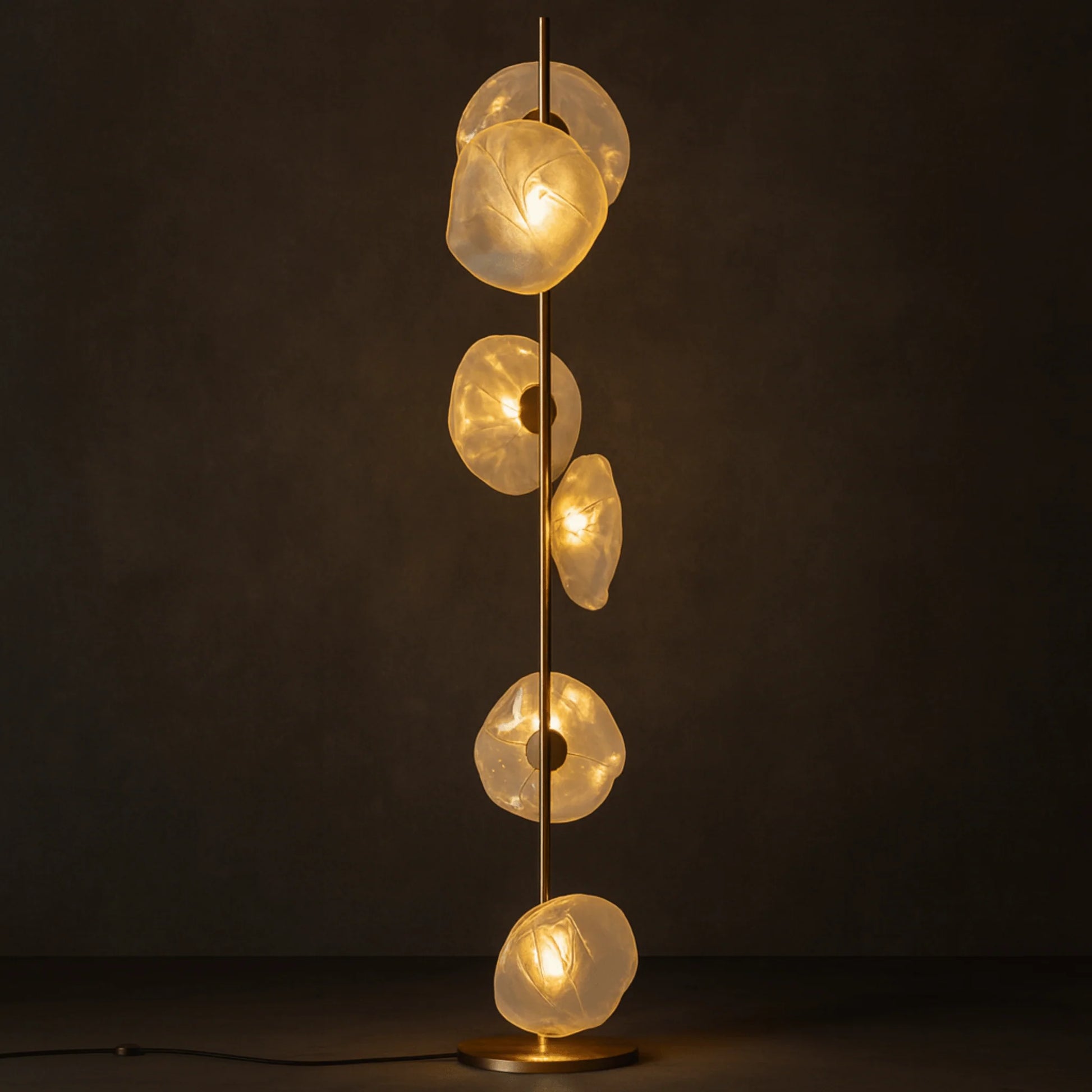 Modern floor lamp with a slim metallic stand featuring multiple organic, glowing glass shades arranged vertically against a dark, moody background.