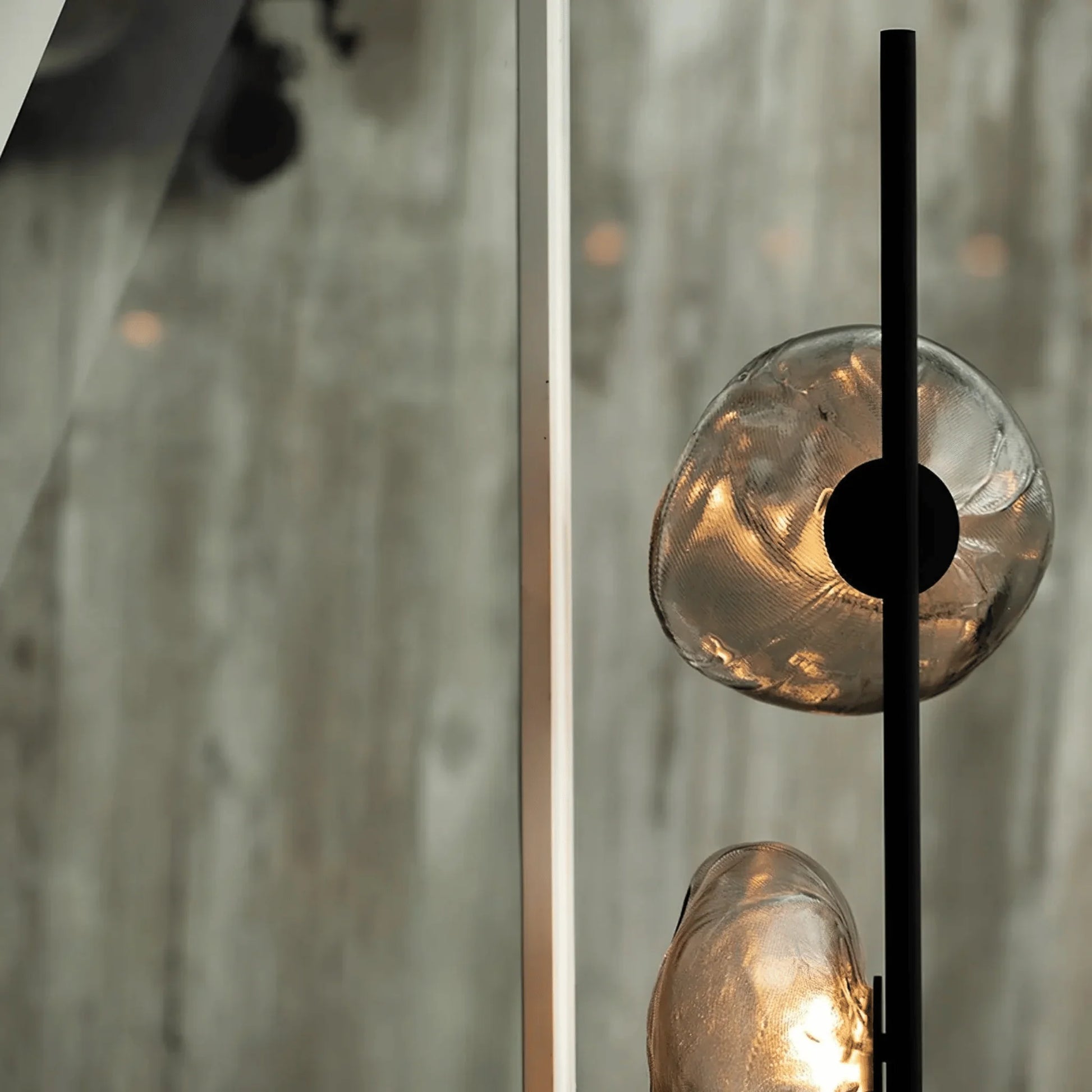 Close-up of a modern glass LED floor lamp with textured, organic-shaped glass globes emitting a warm glow on a black metal stem.