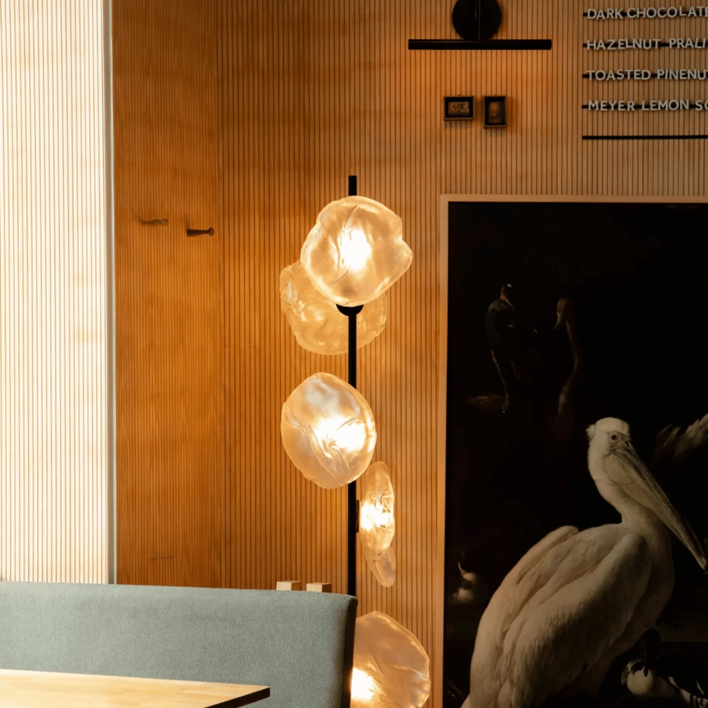 Modern glass LED floor lamp featuring glowing, organic-shaped textured globes on a black stand, set against a contemporary wooden slatted wall.