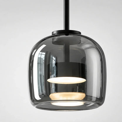 Modern pendant light featuring a rounded, smoked glass shade with a black metal fixture and warm internal illumination against a plain background.