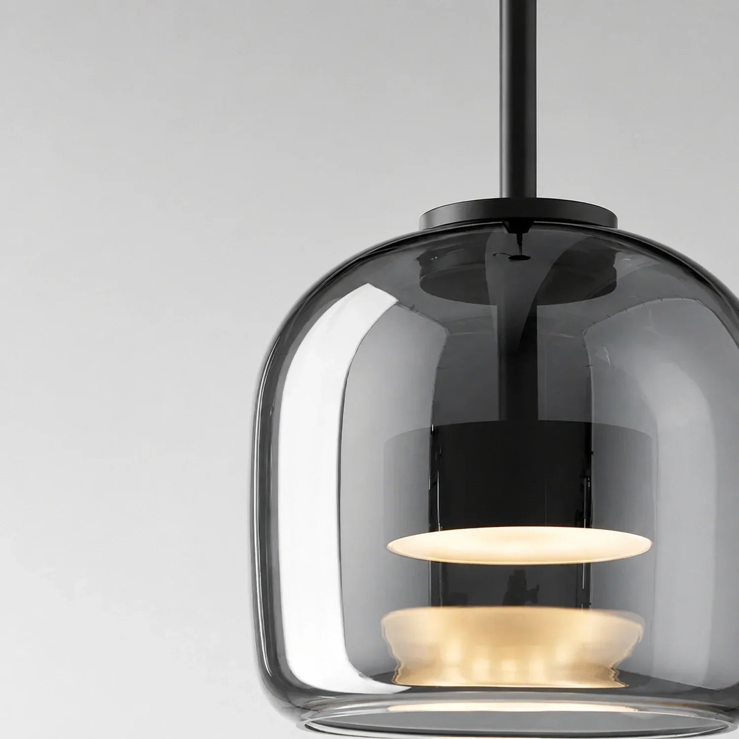 Modern pendant light featuring a rounded, smoked glass shade with a black metal stem and internal glowing light source against a plain grey background.