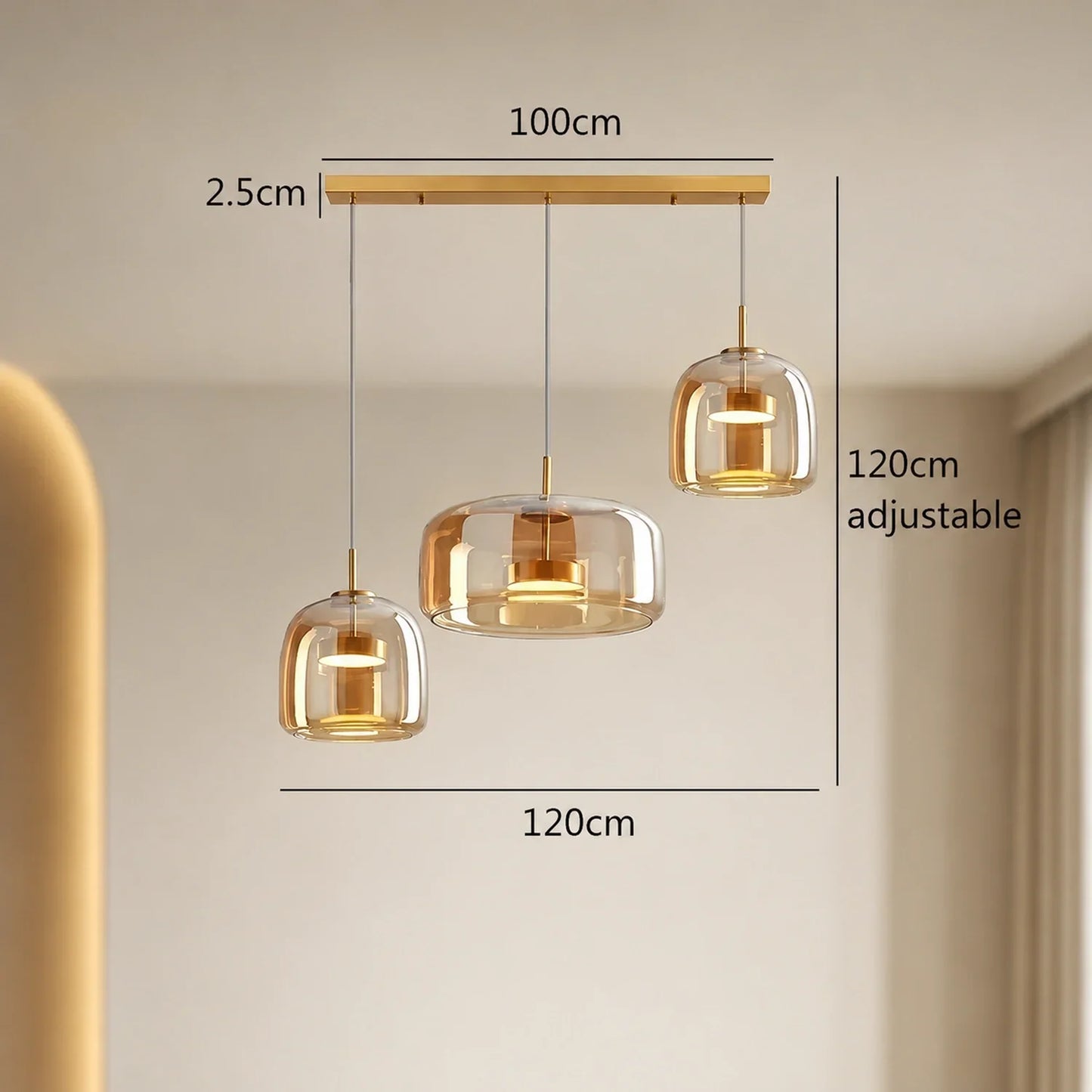 Modern linear triple head pendant light with amber glass shades and gold fittings, showing dimensions for height and width on a neutral background.
