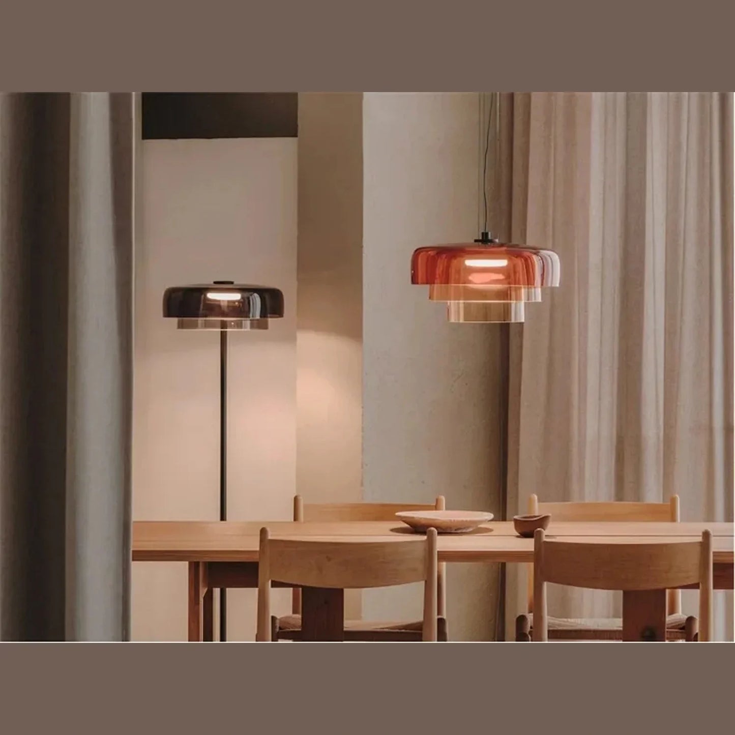 Modern tiered glass pendant light with integrated LED, suspended above a wooden dining table in a contemporary interior with matching floor lamp.