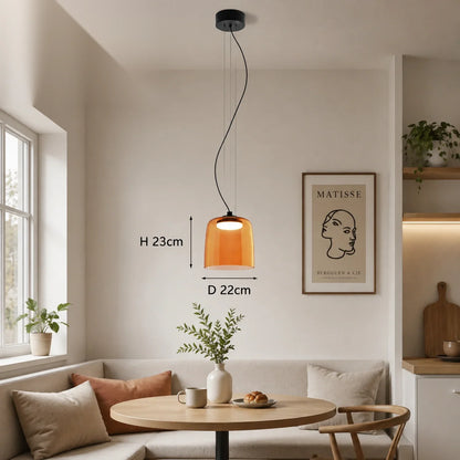Modern orange glass pendant light with integrated LED hanging above a dining table, showing 22cm diameter and 23cm height dimensions in a kitchen.