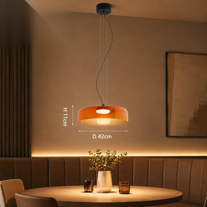 Modern orange glass pendant light with integrated LED, 42cm diameter, suspended above a dining table in a contemporary interior setting.