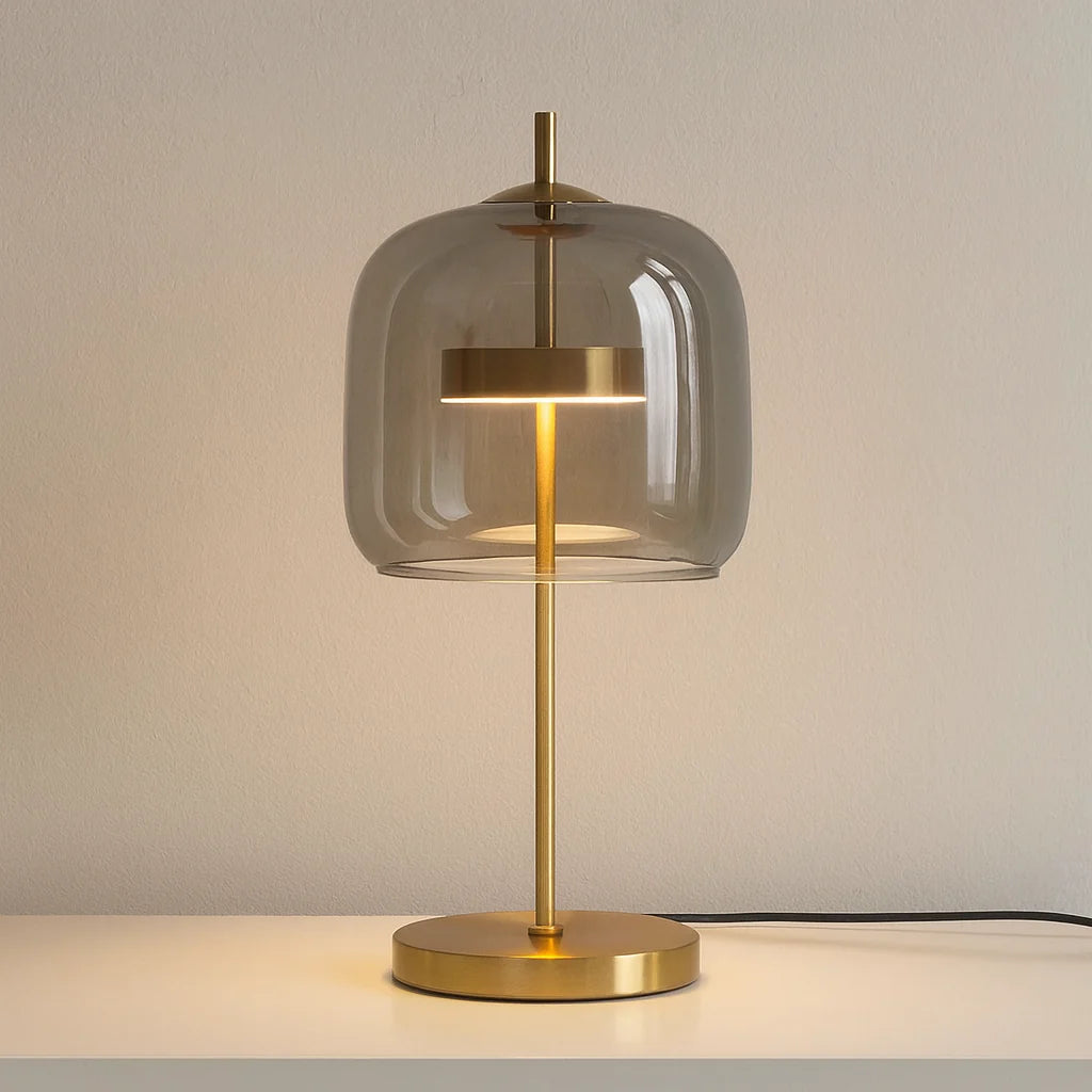 Modern table lamp featuring a smoke grey glass dome shade and a sleek gold metal base, perfect as a stylish bedside or desk light for your home.