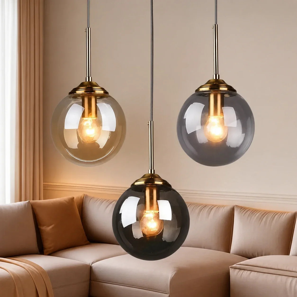 Three modern globe glass pendant lights with brass fittings hanging above a beige sofa in a contemporary living room interior.
