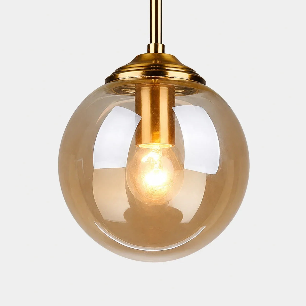 Modern globe pendant light featuring a warm tinted glass shade and a polished brass fitting, perfect for stylish bedroom or kitchen interior lighting.