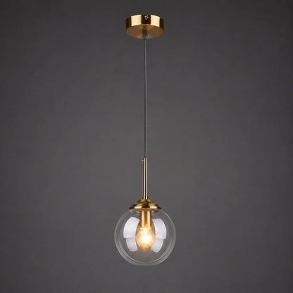 Modern globe pendant light with a transparent glass shade and brass finish ceiling rose, perfect for stylish bedroom or kitchen interior lighting.