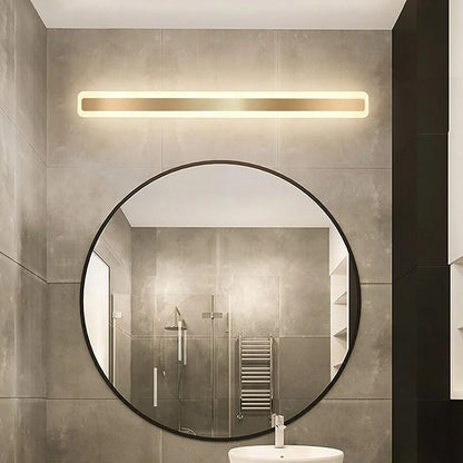 Modern linear LED bathroom wall light with a gold finish mounted above a large circular mirror in a contemporary tiled bathroom setting.
