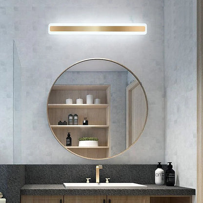 Modern linear LED bathroom wall light with a gold finish mounted above a circular mirror in a contemporary bathroom vanity setting with white light.