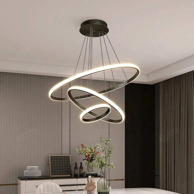 Modern black three-ring LED flush mount ceiling light with adjustable cables, illuminating a contemporary dining room with a warm, ambient glow.