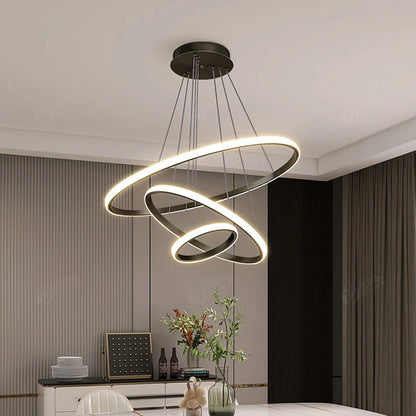 Modern black three-ring LED flush mount ceiling light with adjustable cables, illuminating a contemporary dining room with a warm, ambient glow.