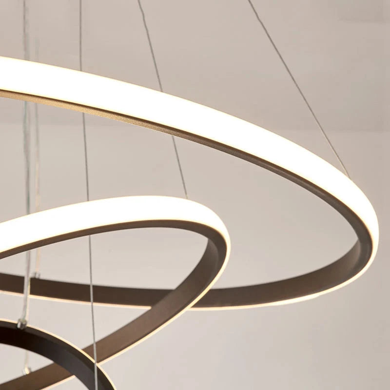 Close-up of a modern LED ceiling light featuring three illuminated circular rings suspended by thin wires, creating a contemporary layered lighting effect.