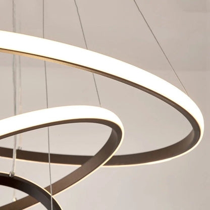 Close-up of a modern LED ceiling light featuring three illuminated circular rings suspended by thin wires, creating a contemporary layered lighting effect.