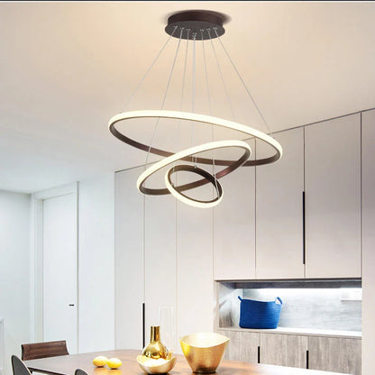Modern three-ring LED ceiling light suspended above a dining table in a contemporary kitchen, featuring a sleek design with warm, dimmable illumination.