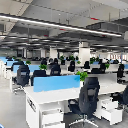 Modern black linear LED pendant lights suspended from an industrial ceiling in a bright, open-plan office space with white desks and black chairs.