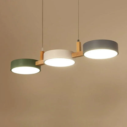 Modern 3-light pendant featuring three circular shades in green, white and grey, connected by natural wood accents and suspended from the ceiling.